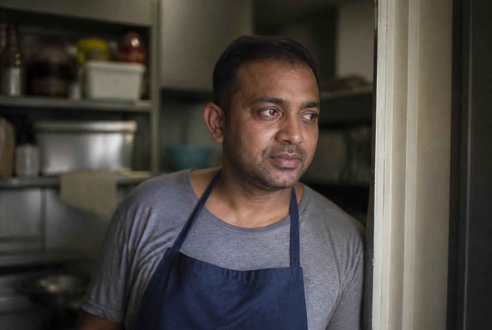 A kitchen worker smiling, holding a tray