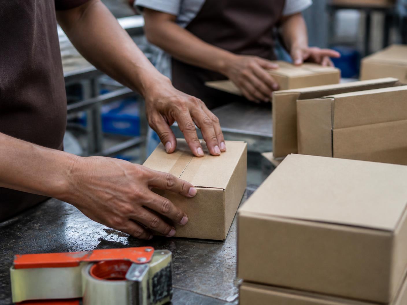 Hands assembling healthy food boxes on a production line